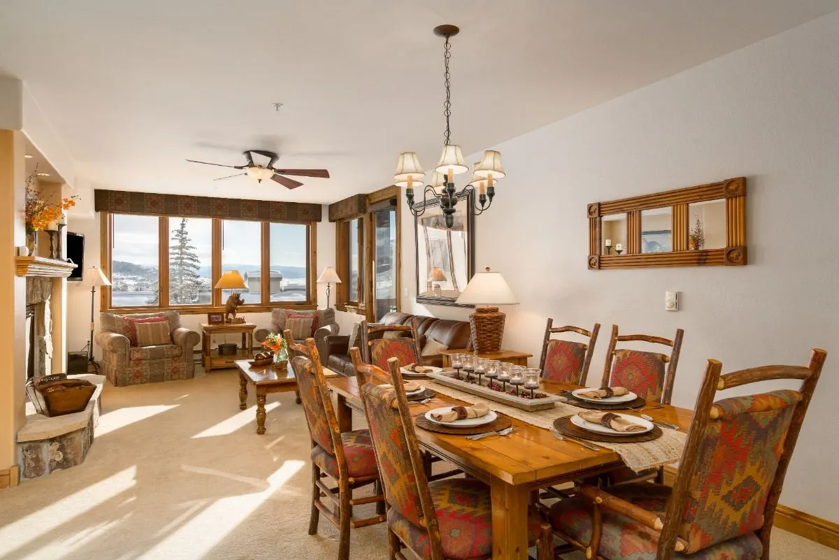 Open-plan living and dining space with a generous table, fireplace, and plush seating. Large windows frame views of the outdoors, while the layout offers seamless flow between relaxation and mealtimes.