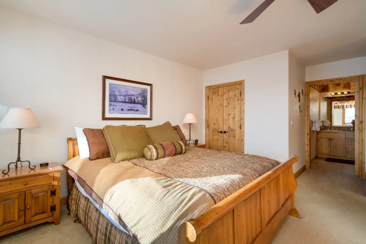A bright, spacious bedroom with a large bed and wooden furniture. Sunlight streams through the window, illuminating the inviting decor and highlighting the comfortable surroundings that offer a perfect retreat after outdoor activities.
