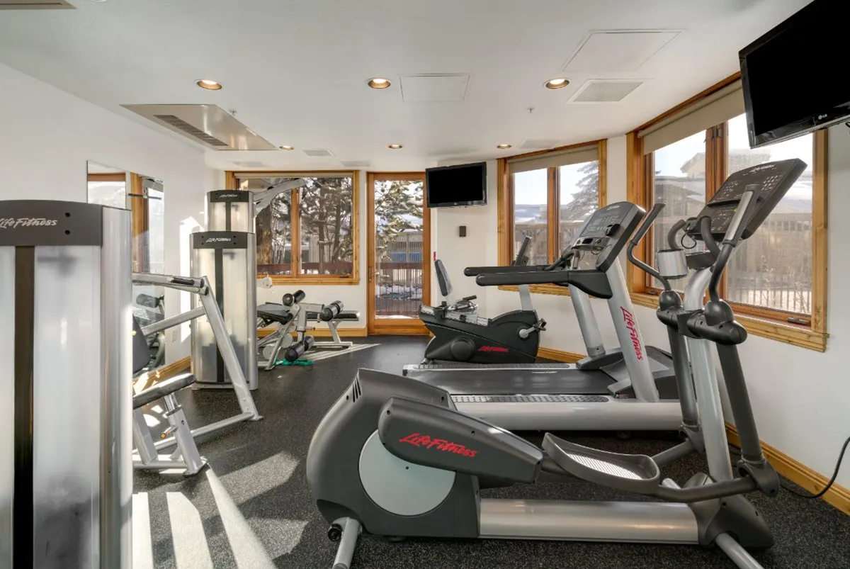 A modern fitness center filled with treadmills, elliptical machines, strength-training equipment, and expansive windows letting in natural light. The clean, motivating atmosphere encourages an active lifestyle.
