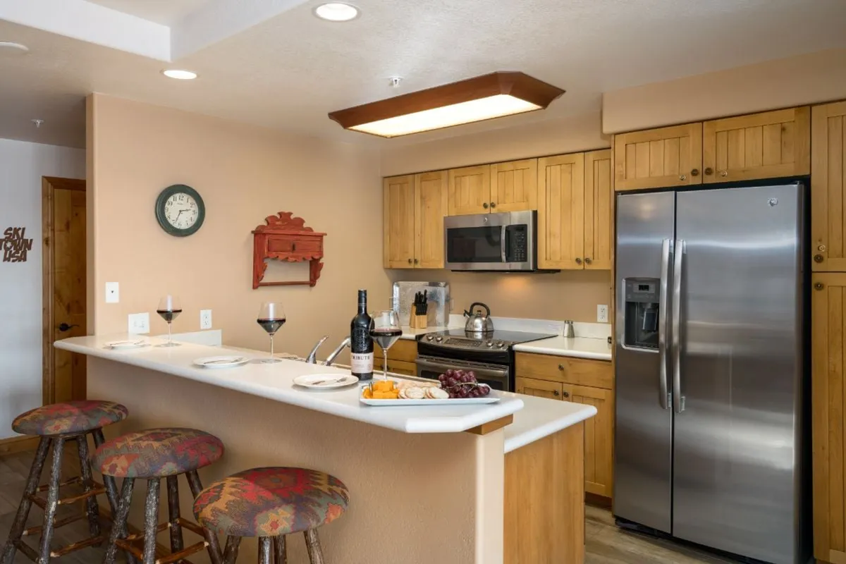 A modern kitchen island set for entertaining, complete with wine glasses and a food platter, surrounded by stools. The space is clearly designed for socializing, casual gatherings, and celebratory toasts.