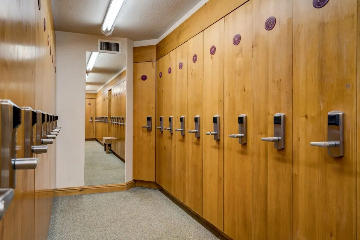 A functional locker room with clean wooden lockers, a mirror, and a bright doorway, providing a practical and comfortable transition space for residents and guests.